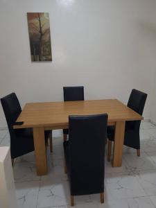 una mesa de madera con sillas negras alrededor en Tapis Guest House, en Brikama