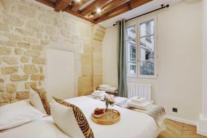 um quarto com uma cama branca e uma parede de pedra em Cocon- Place des Vosges - Le Marais 2 em Paris