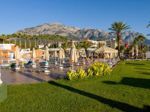 a resort with chairs and umbrellas and mountains in the background at AQI Hydros Club in Kemer