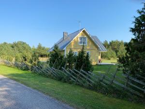 a wooden house with a fence in front of it at Muratsi Holiday Cottages in Kuressaare