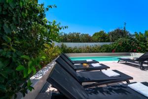 a swimming pool with a table and chairs next to it at Thalassa Luxury Villa in Ialysos