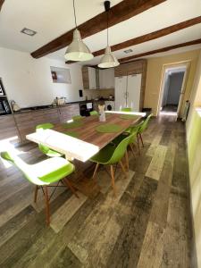 a dining room with a wooden table and green chairs at Casa Villa Franca in Llamas de la Ribera