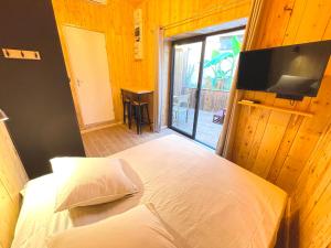 Schlafzimmer mit einem Bett und einem Flachbild-TV in der Unterkunft myinsolite - Cocon Tropical, jacuzzi, énigme in Vauvert
