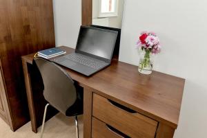 a laptop computer on a wooden desk with a vase of flowers at Derby City Centre, Bright, Spacious, and Airy Apartments - 112 Duffield Road in Derby