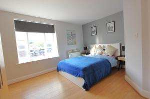 a bedroom with a blue bed and a window at Lovely 2 Bed 2 Bath Flat & Parking by CozyNest in Reading