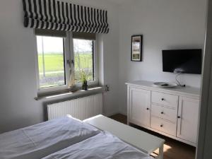 Tümlauer KoogにあるAppartements unter Reetのベッドルーム(ベッド1台、テレビ、窓付)