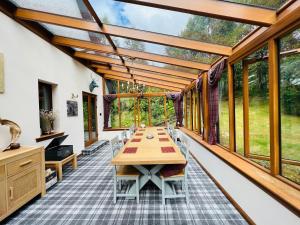 a conservatory with a table and chairs and windows at Tarmachan Cottage - West Highland Getaway in Fort William