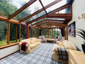 a living room with a conservatory with glass windows at Tarmachan Cottage - West Highland Getaway in Fort William