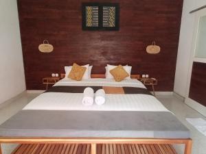 a bedroom with a bed with two white shoes on it at THE OWN PENIDA COTTAGE & SPA in Nusa Penida