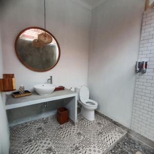 a bathroom with a sink and a toilet and a mirror at THE OWN PENIDA COTTAGE & SPA in Nusa Penida