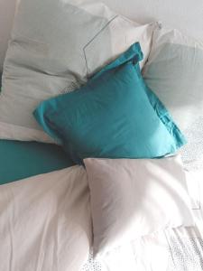 a pile of pillows on a bed with a blue pillow at Chambre #2 dans appartement partagé - Proche des Vosges in Thann