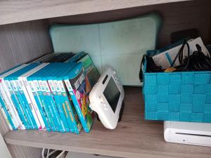 Ein Regal mit Büchern und einem Wii Controller. in der Unterkunft Chambre #2 dans appartement partagé - Proche des Vosges in Thann