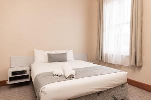 a bedroom with a large white bed with a window at Barwon Heads Hotel in Barwon Heads