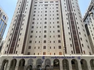 a tall white building with a sign in front of it at Al Ansar Golden Tulip in Al Madinah