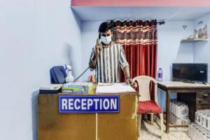 een man met een masker aan een bureau met een bord bij Hotel V R Loge By WB Inn in Nagpur