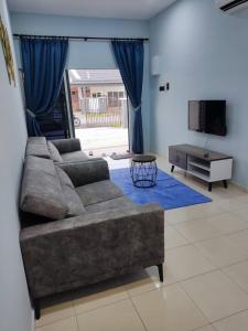a living room with a couch and a tv at Bahagia 137 Homestay with private pool in Port Dickson