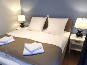 - une chambre avec un lit avec des draps blancs et 2 lampes dans l'établissement Villa Camenia, à Kühlungsborn
