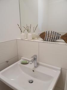 La salle de bains blanche est pourvue d'un lavabo et d'un miroir. dans l'établissement Villa Camenia, à Kühlungsborn