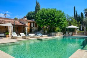 a swimming pool with chairs and umbrellas next to a house at La Maison de Platane B&B in Fayence