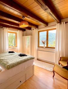 a bedroom with a bed and two windows at Ferienhaus mit Zirbitzblick in Mönchegg