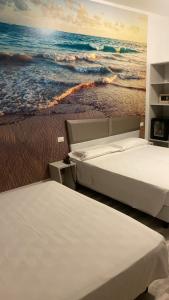 duas camas num quarto com uma pintura do oceano em Hotel Giardinetto Al Sant'Orsola em Bolonha