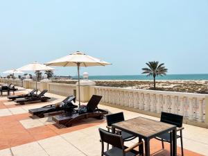 a patio with tables and chairs and the beach at Sea La View Family Home in Ras al Khaimah