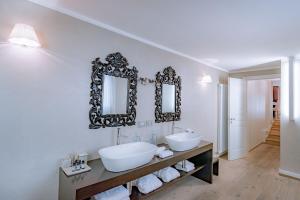 La salle de bains est pourvue de 2 lavabos et de miroirs sur le mur. dans l'établissement TownHouse 33, à Milan