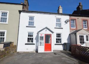 a white building with a red door at Old Post Office - Hot Tub, Real Fire, Cumbrian Lakes Coastal Cottage in St Bees