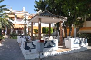a gazebo with white chairs and tables in front of a house at Costahispania 308 in Gran Alacant