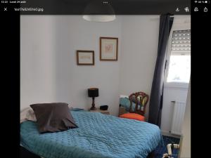 ein Schlafzimmer mit einem Bett mit blauer Decke und einem Fenster in der Unterkunft Appartement cosy la trinité sur mer in La Trinité-sur-Mer