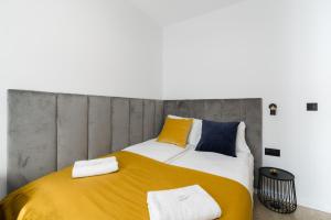 sypialnia z dużym łóżkiem z żółtymi i niebieskimi poduszkami w obiekcie Niedziałkowskiego 25 Apartments Stary Browar City Center by Renters Prestige w Poznaniu