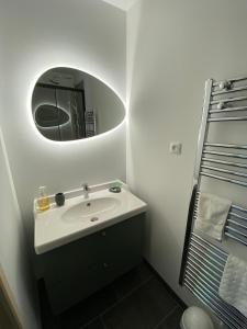 a white bathroom with a sink and a mirror at La Maison de la Rose in &Eacute;tretat
