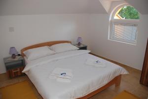 - une chambre avec un lit blanc et 2 serviettes dans l'établissement Vila Simic Srebrno Jezero, à Ostrovo