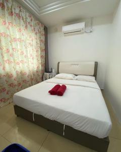 a bed with two red pillows on it in a room at D' Anjung Inn in Tangkak