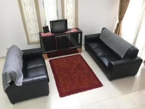 two black leather chairs and a television in a living room at KUL Rest House in Labu