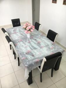 KUL Rest House في Labu: طاولة عليها قطعة قماش و مزهرية من الزهور