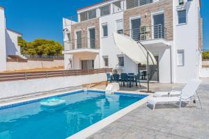 a swimming pool with two chairs and a house at Modern, Cheerful & Dream Catching Villa in Corinth in Isthmia