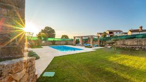 a backyard with a swimming pool and a stone wall at Villa Campiello heated pool in Vrbnik