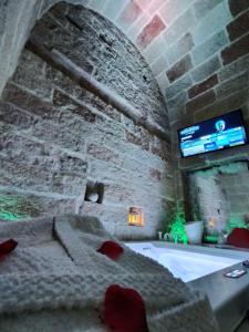 um quarto com uma banheira e uma televisão numa parede de tijolos em Dofely - Suite by the Sea em Polignano a Mare