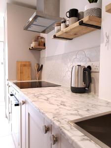 a kitchen with white cabinets and a marble counter top at Self-contained annexe excellent location in Saltdean