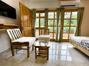 a bedroom with two chairs and a bed and a window at The Wild Yak in Mandi