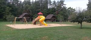 a playground with a yellow slide in a park at Kempings Sniedzes in Ķegums