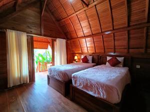 a bedroom with two beds in a wooden room at Dekara Cottages in Nusa Penida