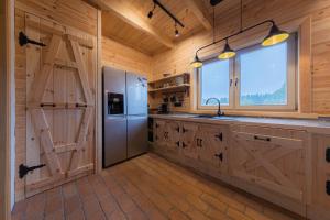 a kitchen with wooden cabinets and a refrigerator and a window at Apartament w Bukowej Chacie in Mörken