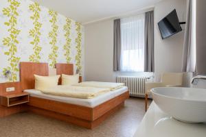 a bedroom with a bed and a tub and a sink at Hotel Krone Rüdesheim in Rüdesheim am Rhein