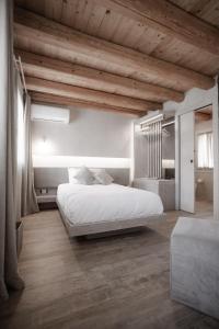 Schlafzimmer mit einem großen weißen Bett und Holzdecken in der Unterkunft Locanda MaMaGiò in Valdobbiadene