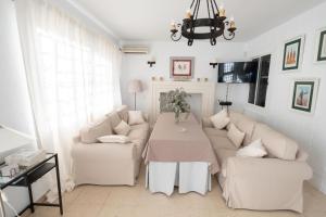 uma sala de estar com um sofá e uma mesa em Agradable Villa con piscina em Sevilha