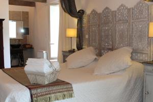 um quarto com uma cama grande com lençóis brancos e almofadas em La maison Cayré em Mirandol-Bourgnounac