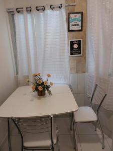 un tavolo bianco con due sedie e un vaso di fiori sopra di Apartamento Cond. Privê em Caiobá 2 quadras da beira mar próximo ao Restaurante Casa do Camarão a Matinhos Altre 6 foto