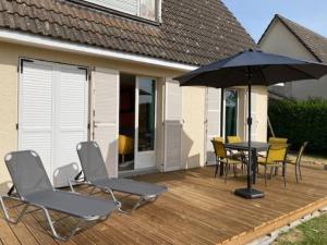 a deck with a table and chairs and an umbrella at LE GÎTE DES BLEUETS in Cany-Barville